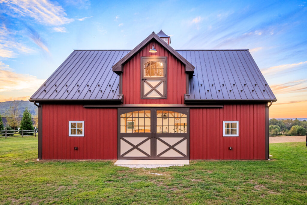 horse barn with red siding, sliding barn doors with glass, and loft door